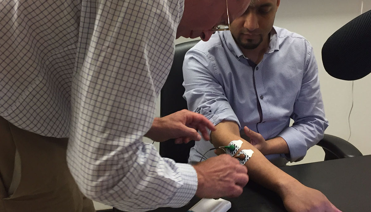 Professor Stuart Baker fits stroke device to man's arm